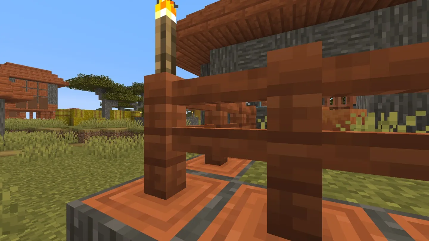 Acacia houses and a fence viewed from the recorded first player spawn. In-game screenshot, Java 26.3.