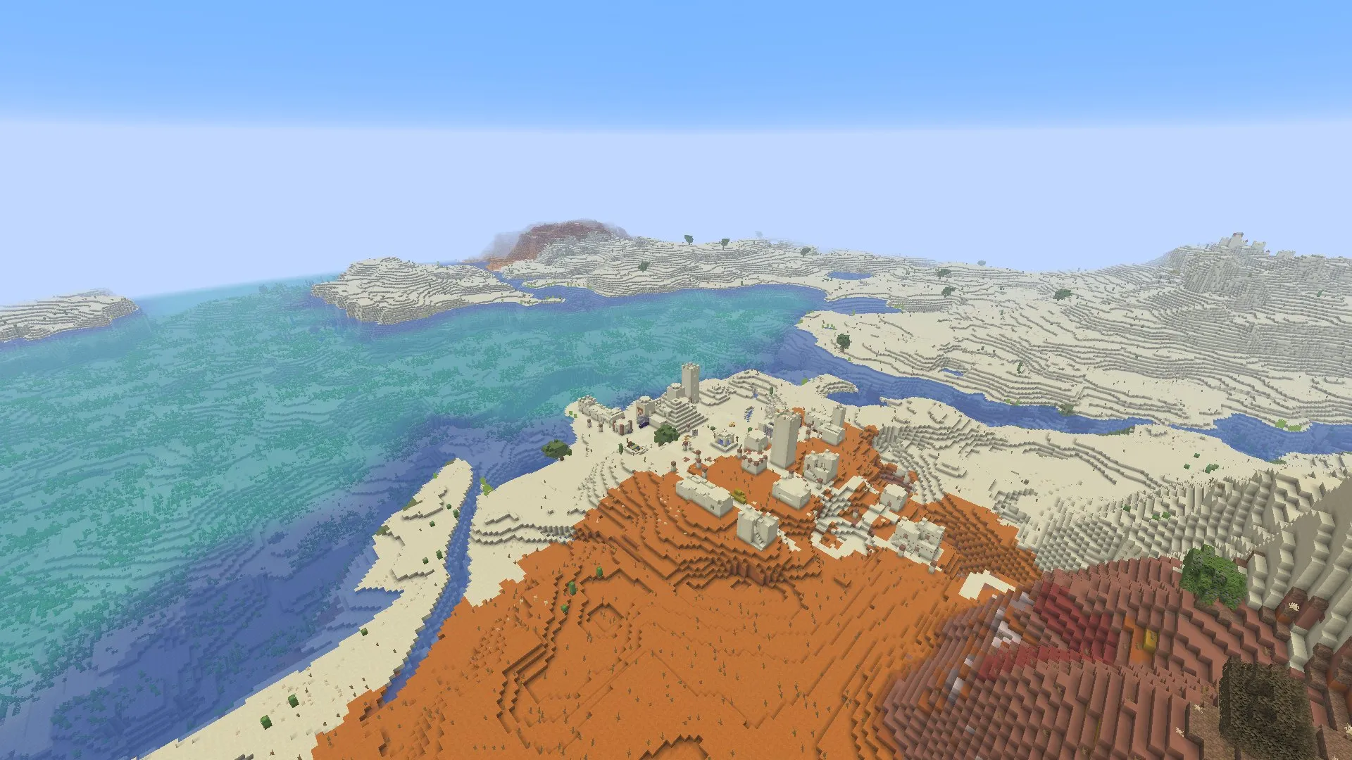 A sandstone desert temple and village beside orange badlands and coastal water. In-game screenshot, Java 26.3.