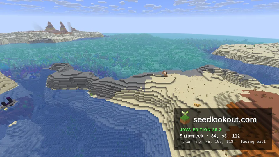 Sand and stone shore beside a coral sea, with tall orange badlands spires on the far horizon