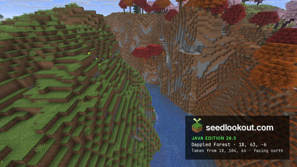 River running through a steep valley between a grassy slope and red and orange dappled forest