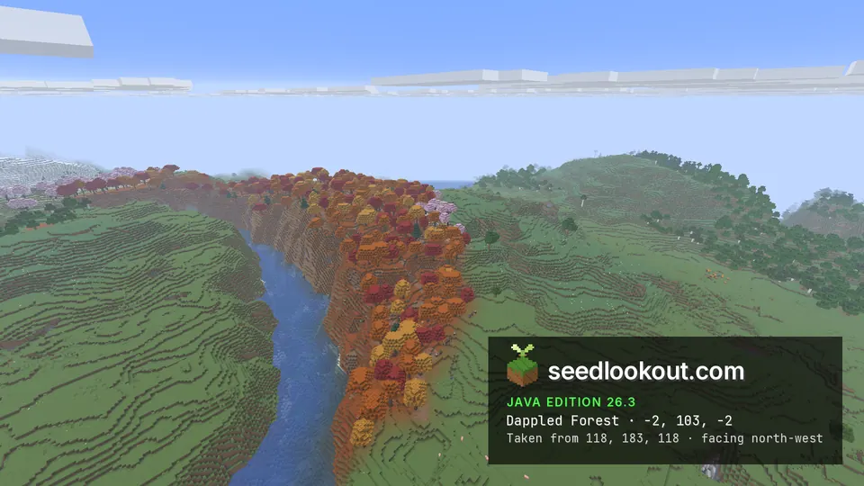 Band of red, orange and yellow trees along the rim of a steep river gorge in green grassy hills