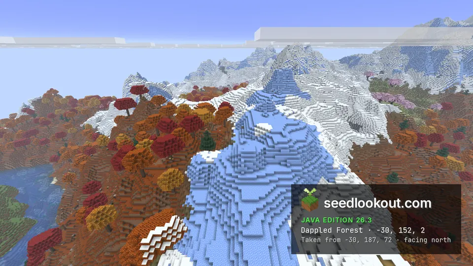 Red and orange dappled forest on both sides of a ridge of snow and pale blue ice, snowy peaks behind