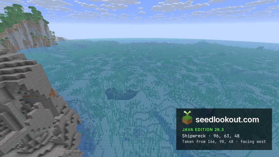Dark shipwreck shape on the sea floor in a wide bay, a stone cliff on the left